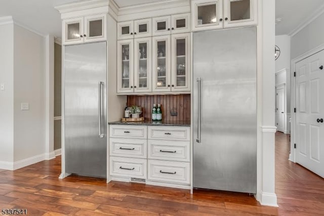 kitchen featuring stainless steel built in refrigerator, glass insert cabinets, and white cabinets