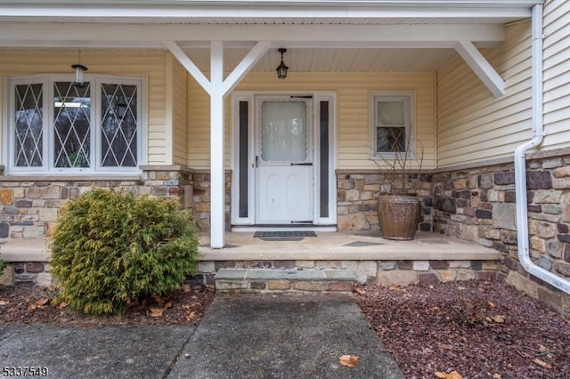 view of exterior entry featuring a porch and stone siding