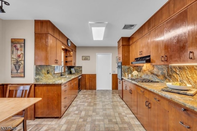 kitchen with gas cooktop, under cabinet range hood, a sink, visible vents, and open shelves