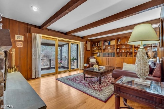 living area with built in features, beam ceiling, wood walls, and wood finished floors