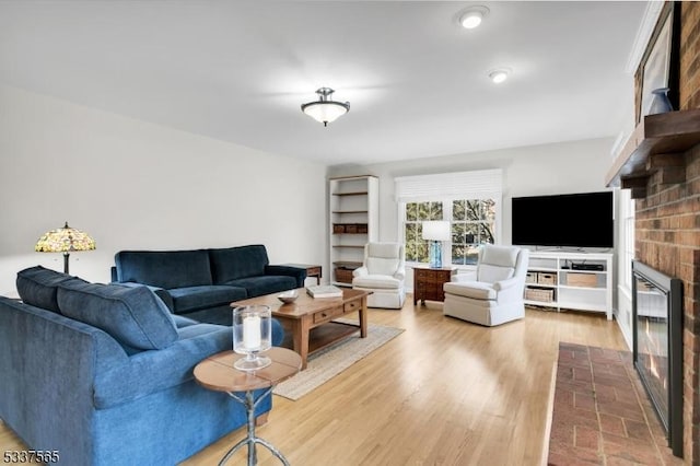 living room with a brick fireplace and wood finished floors