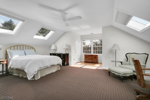 bedroom featuring lofted ceiling with skylight, light carpet, baseboards, and a ceiling fan