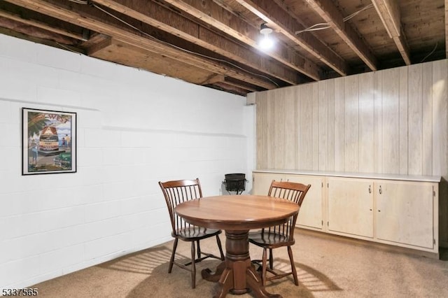 dining space featuring concrete block wall and light carpet