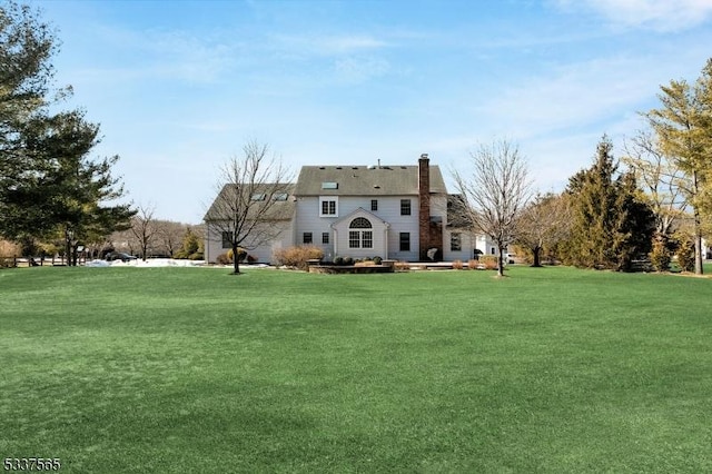 back of property featuring a chimney and a yard