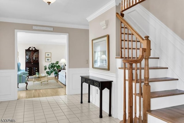 stairs with wainscoting, crown molding, a decorative wall, and tile patterned floors