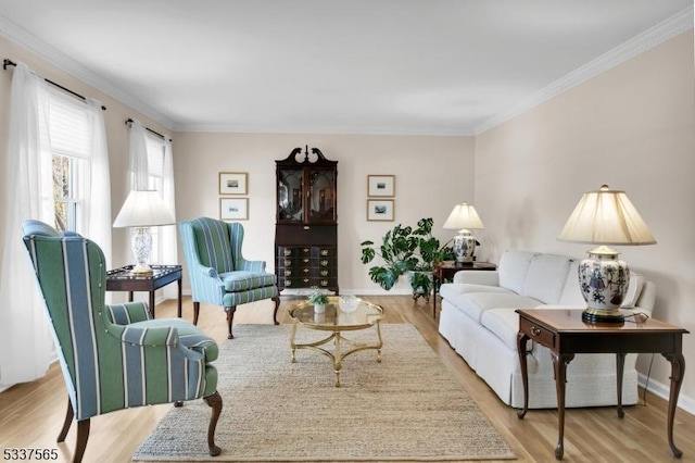 living area with baseboards, light wood-type flooring, and crown molding