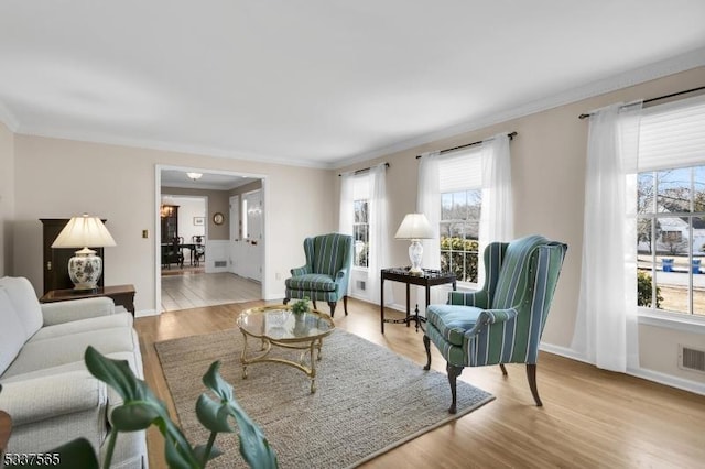 living room featuring light wood-type flooring, a wealth of natural light, ornamental molding, and baseboards