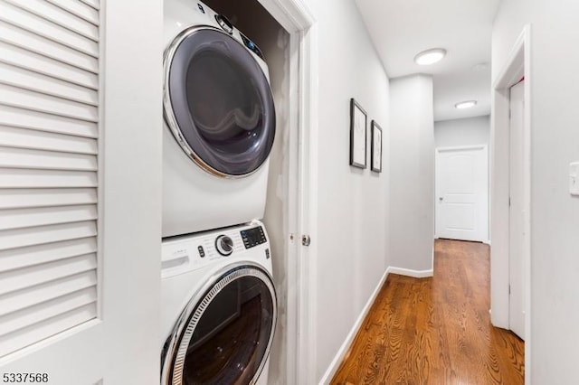 laundry room with hardwood / wood-style floors and stacked washer and clothes dryer