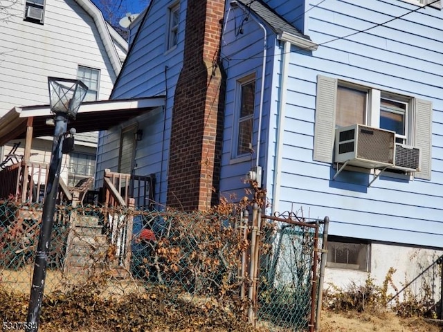 view of side of property with a chimney, fence, and cooling unit