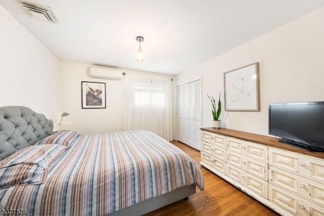 bedroom with hardwood / wood-style flooring, a closet, and an AC wall unit