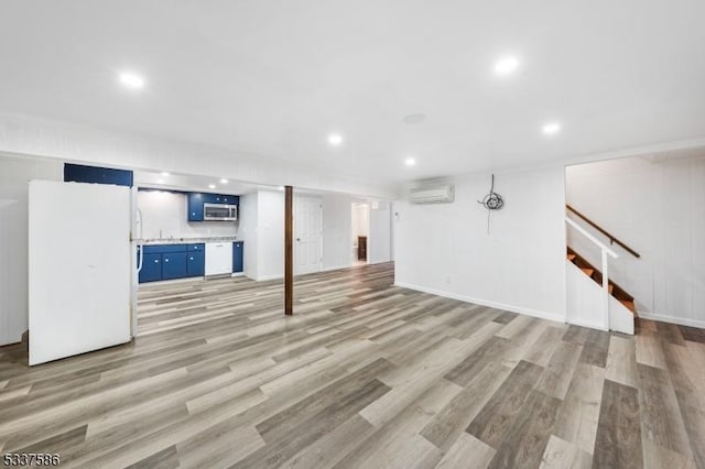 basement with light hardwood / wood-style floors, an AC wall unit, and white fridge