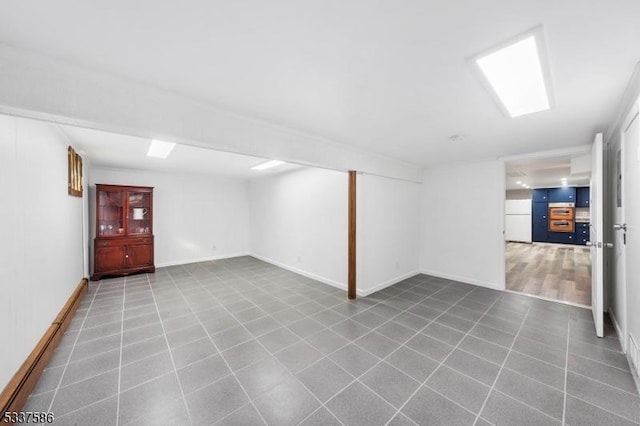 basement with white refrigerator and tile patterned flooring