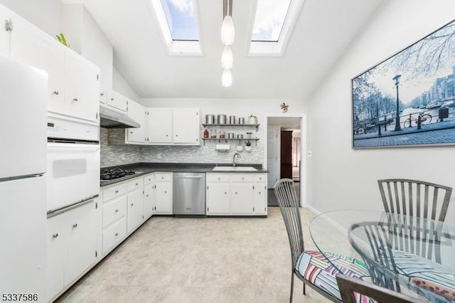 kitchen with lofted ceiling with skylight, sink, pendant lighting, stainless steel appliances, and white cabinets