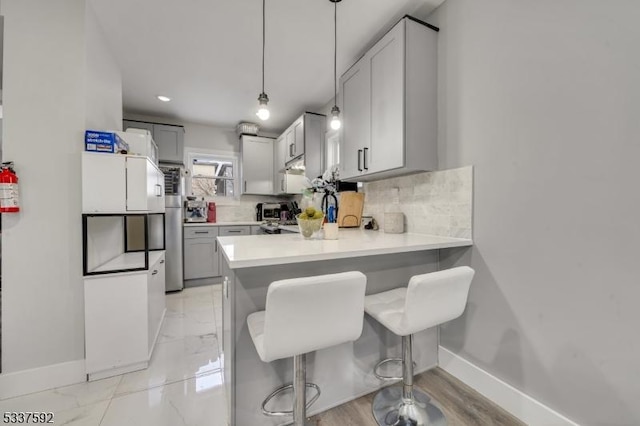 kitchen with decorative light fixtures, a breakfast bar area, decorative backsplash, and kitchen peninsula