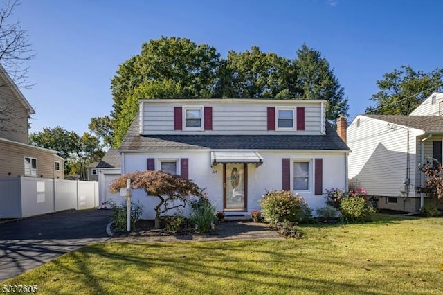 view of front of property featuring a front yard, roof with shingles, driveway, and fence