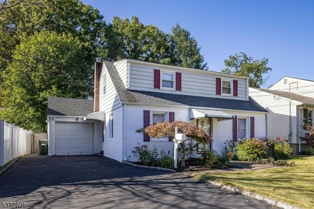 traditional home with aphalt driveway, a shingled roof, a chimney, and fence