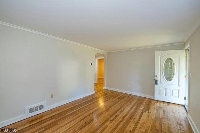 interior space with light wood-type flooring, baseboards, visible vents, and arched walkways