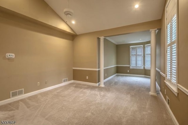 carpeted empty room featuring baseboards, visible vents, vaulted ceiling, and ornate columns