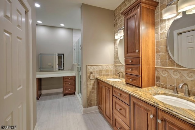 bathroom featuring a stall shower, a sink, tile walls, and double vanity