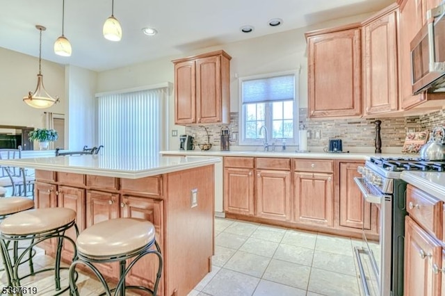 kitchen with a breakfast bar, light brown cabinets, a kitchen island, stainless steel appliances, and light countertops