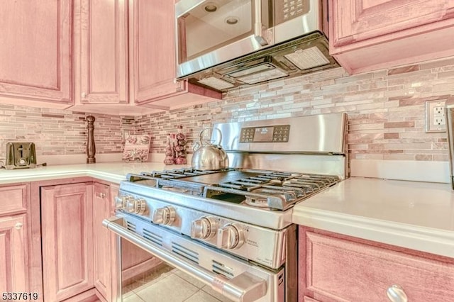 kitchen featuring light brown cabinetry, tile patterned flooring, light countertops, stainless steel appliances, and backsplash