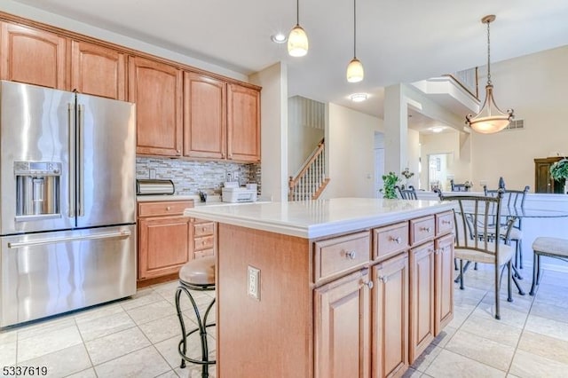 kitchen featuring decorative backsplash, light countertops, high quality fridge, and pendant lighting