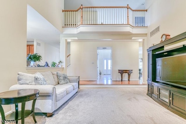 living area with a towering ceiling, baseboards, visible vents, and carpet floors