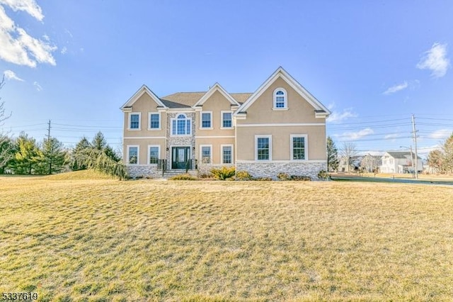 view of front of property featuring a front yard, stone siding, and stucco siding