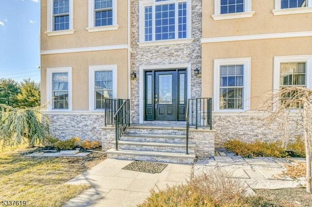 entrance to property featuring stone siding and stucco siding