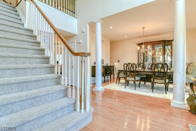 stairs featuring recessed lighting, decorative columns, hardwood / wood-style floors, and a chandelier