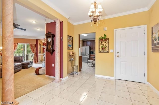 foyer entrance featuring ornate columns, crown molding, ceiling fan with notable chandelier, and light tile patterned floors