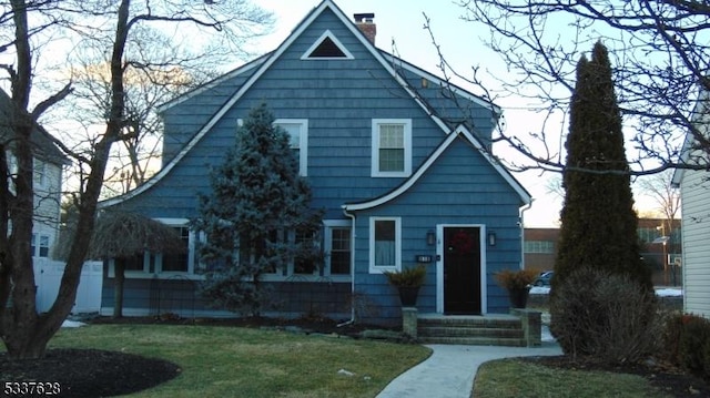 view of front of home with a chimney and a front lawn