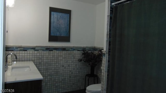 full bathroom with a wainscoted wall, toilet, a shower with curtain, tile walls, and vanity