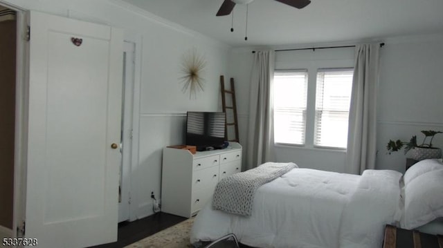 bedroom featuring a ceiling fan, dark wood-style flooring, and ornamental molding