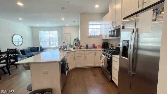 kitchen with sink, appliances with stainless steel finishes, white cabinets, dark hardwood / wood-style flooring, and kitchen peninsula