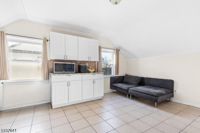 kitchen featuring white cabinetry, vaulted ceiling, and light tile patterned floors