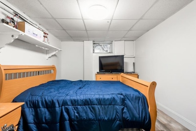 bedroom with light wood-type flooring and a drop ceiling