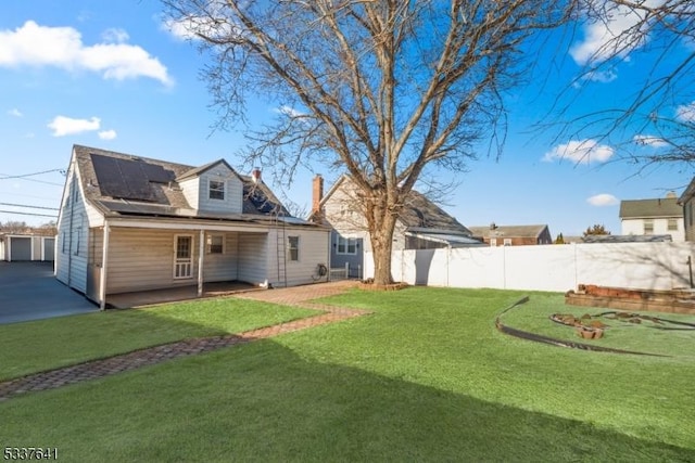 rear view of house featuring a lawn and solar panels