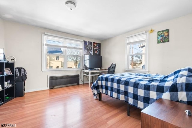 bedroom with radiator heating unit and wood-type flooring