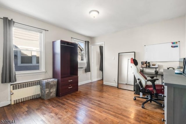 home office with radiator heating unit and dark hardwood / wood-style flooring