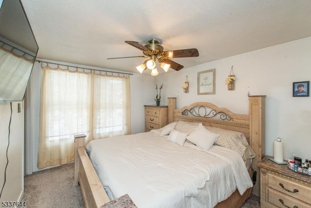 bedroom with ceiling fan, light carpet, and a textured ceiling