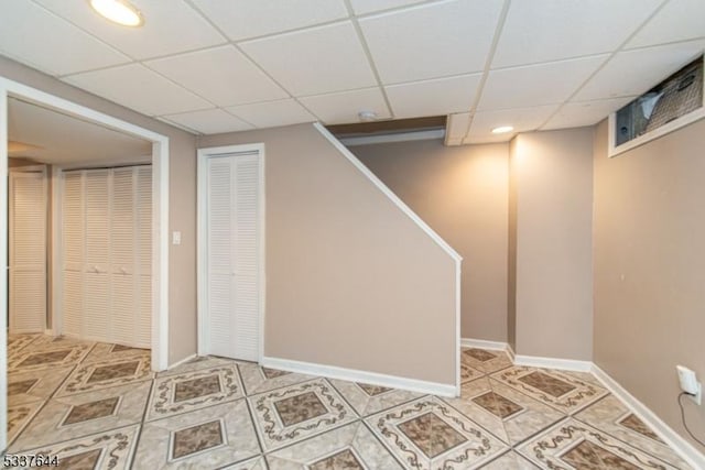 basement with a paneled ceiling and light tile patterned floors