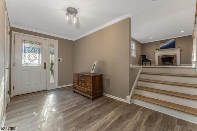 foyer featuring baseboards, wood finished floors, and crown molding