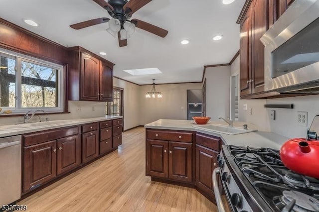 kitchen featuring light countertops, appliances with stainless steel finishes, a skylight, and a sink