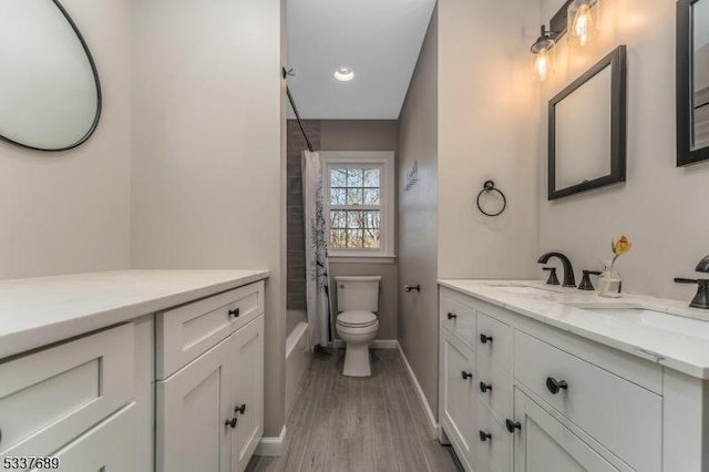 full bathroom with baseboards, toilet, wood finished floors, shower / bath combo with shower curtain, and vanity