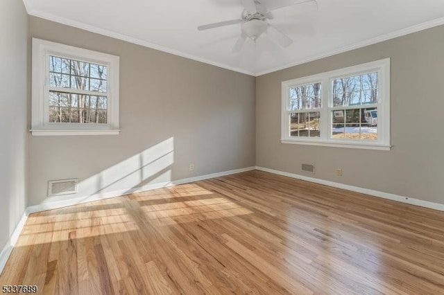 empty room featuring baseboards, visible vents, a ceiling fan, ornamental molding, and wood finished floors