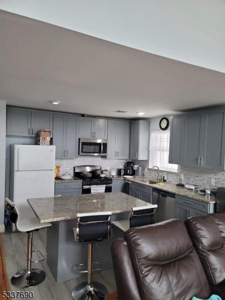 kitchen with appliances with stainless steel finishes, a kitchen bar, a center island, and sink