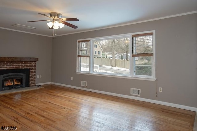 unfurnished living room with ornamental molding, a healthy amount of sunlight, a fireplace, and light wood-type flooring