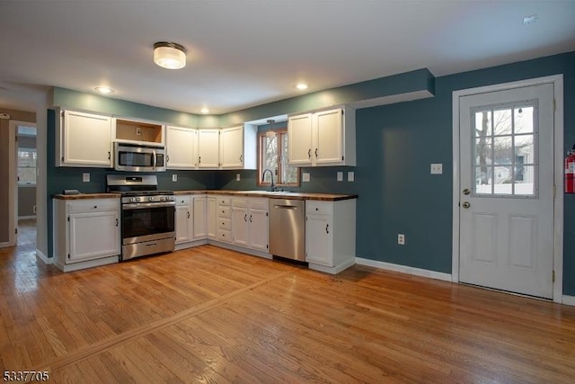 kitchen featuring white cabinetry, stainless steel appliances, sink, and light wood-type flooring