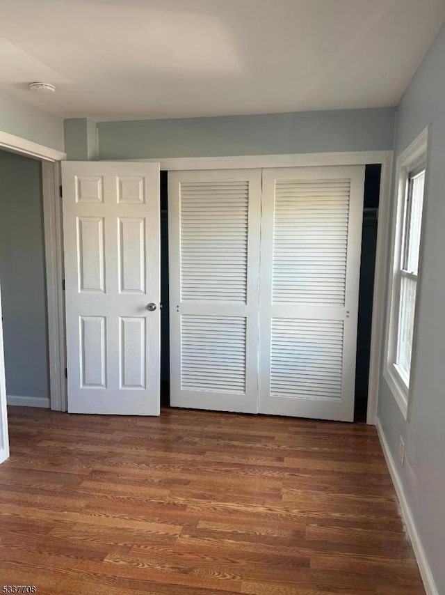 unfurnished bedroom with dark hardwood / wood-style flooring and a closet